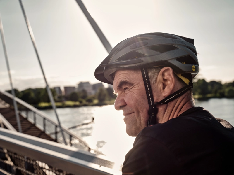 JobRadler auf Fahrradbrücke fährt grinsend in den Feierabend