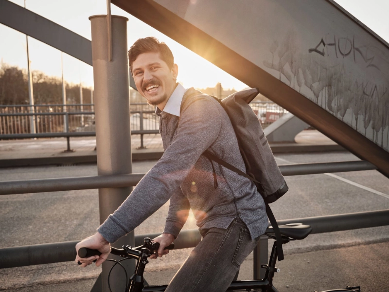 Ein lachender JobRadler fährt im Sonnenuntergang über eine Brücke Ein lachender JobRadler fährt im Sonnenuntergang über eine Brücke