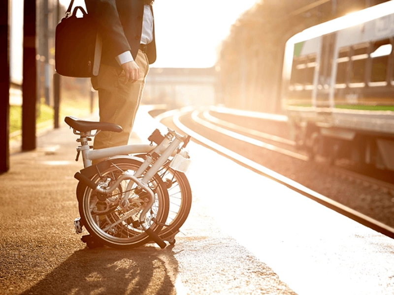 Businessmensch mit Faltrad wartet auf den Zug Businessmensch mit Faltrad wartet auf den Zug